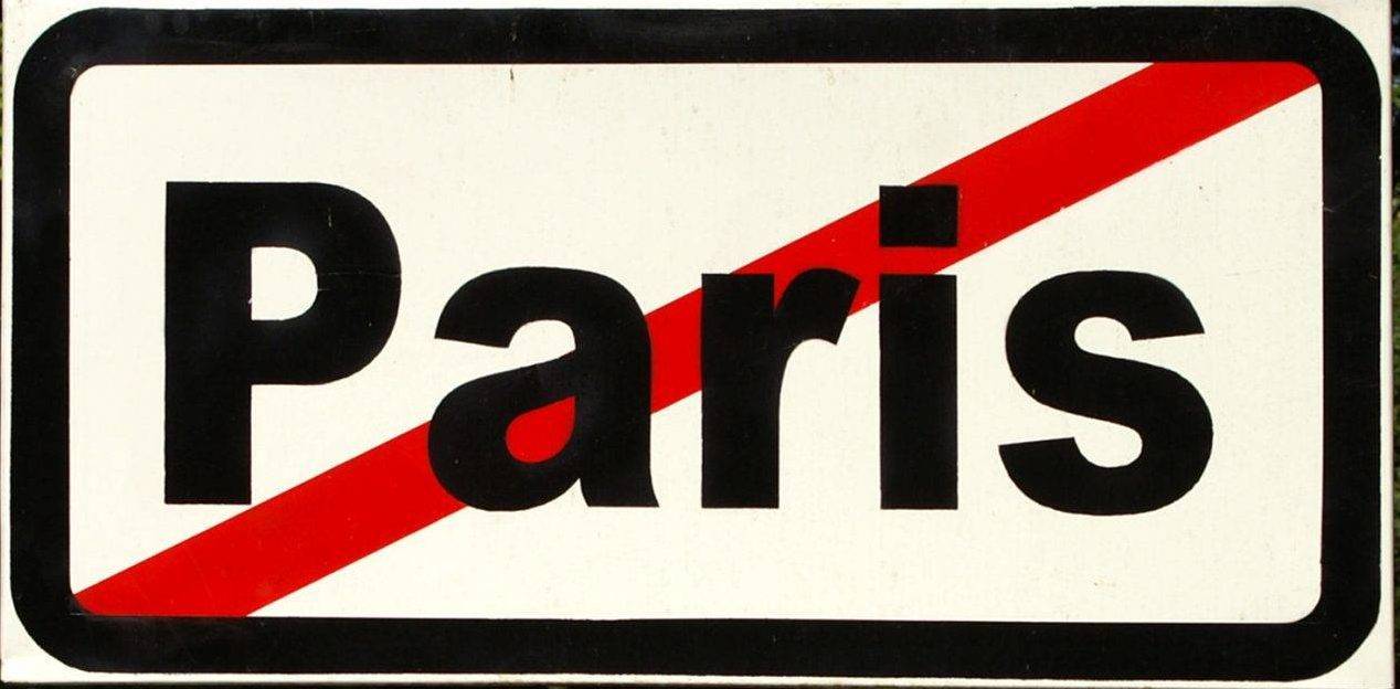 A road sign reading "Paris" with a red diagonal strike-through, carried through the streets of old Bucharest during a performance.